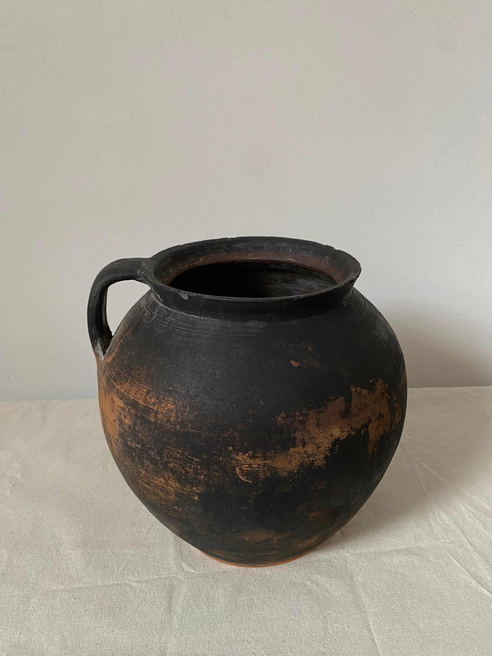 Black terracotta pot with a textured surface on a light gray background