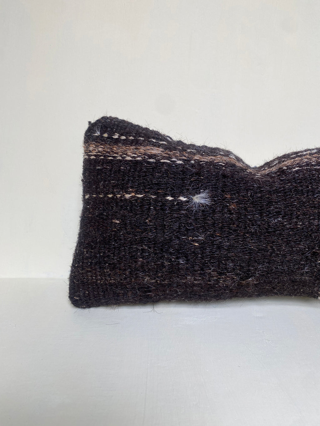 Handwoven brown Turkish lumbar cushion  covermade from 40-year-old vintage wool with subtle stripes and textured finish, styled against a neutral backdrop.