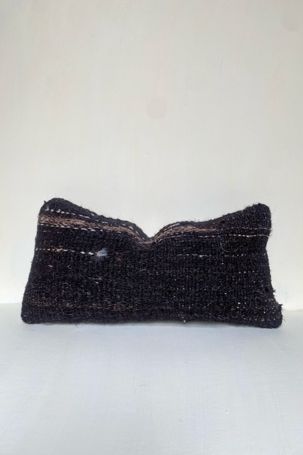 Handwoven brown Turkish lumbar cushion  covermade from 40-year-old vintage wool with subtle stripes and textured finish, styled against a neutral backdrop.