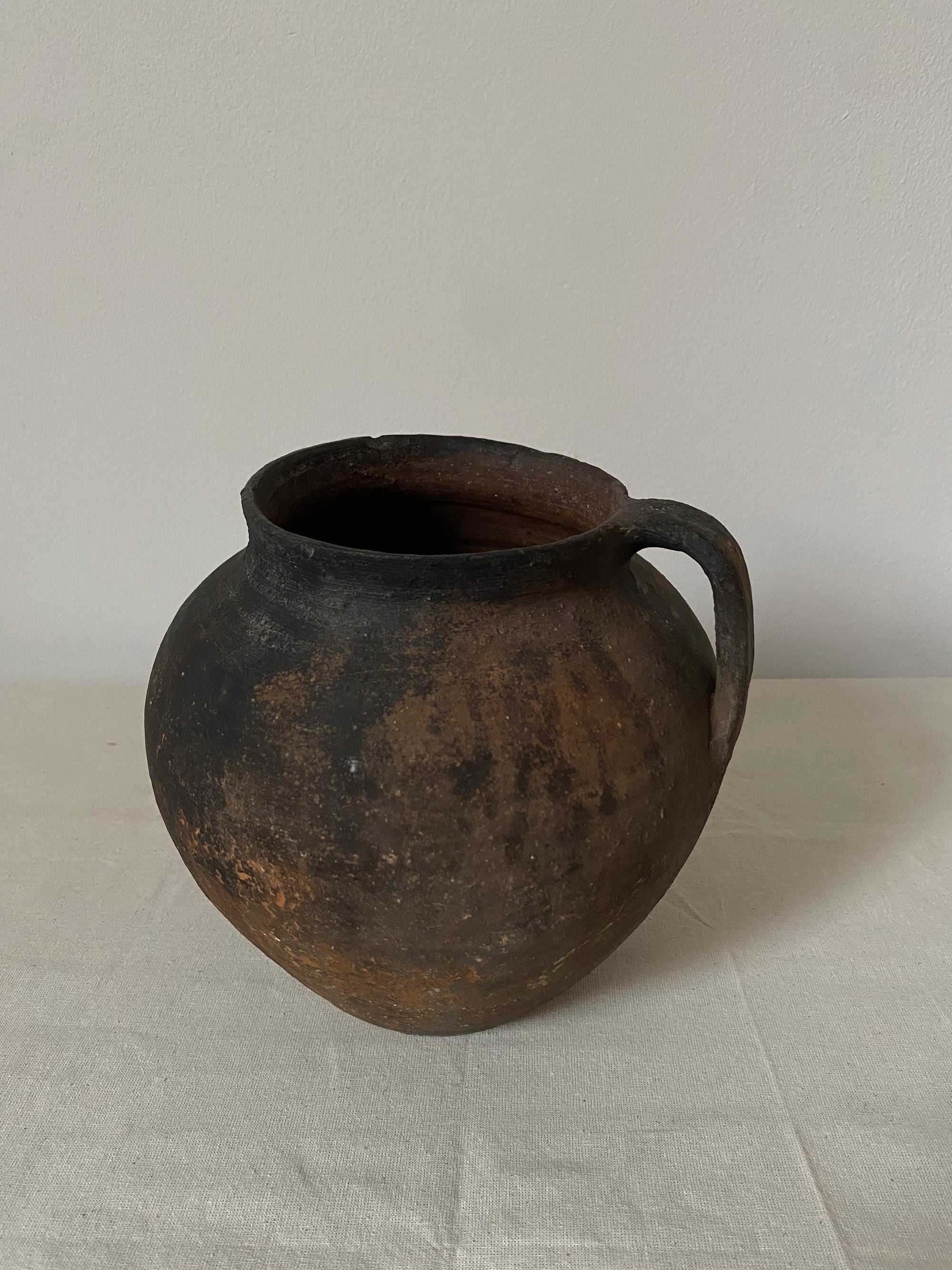 Rustic metal pot on a textured beige background