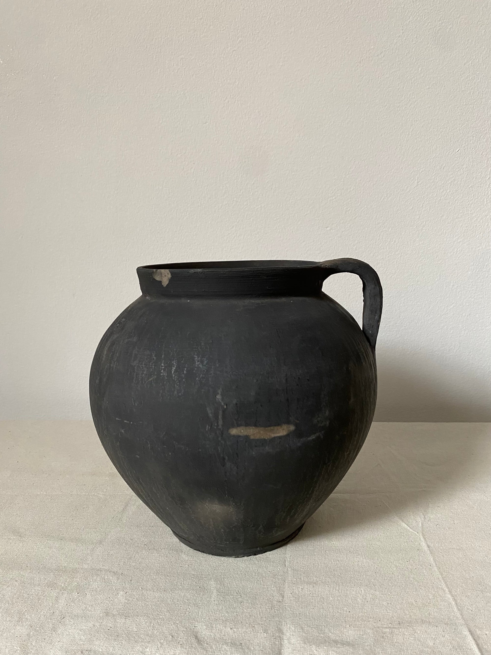 Black antique clay pot on a light background