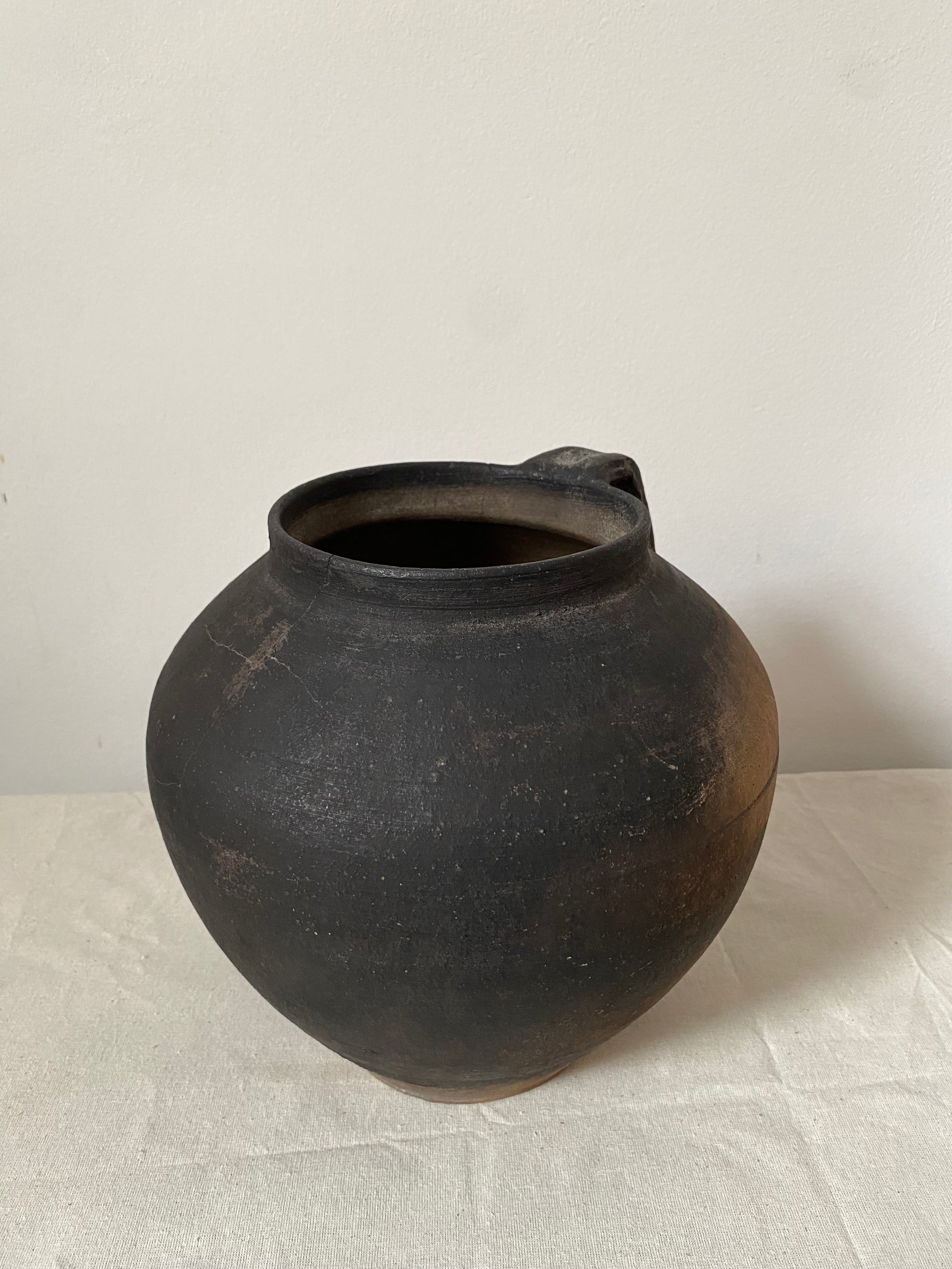Black ceramic pot on a light gray surface with a white background